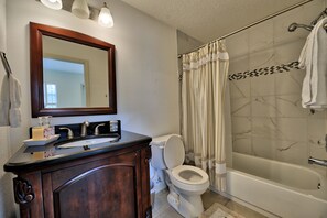 A bathroom with a sink, mirror, toilet, and bathtub.