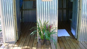 A wooden deck with a sign reading "BATH HOUSE" and two potted plants.