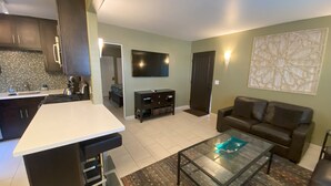 A modern living space with a kitchen, dining area, and a seating area with a sofa and coffee table.