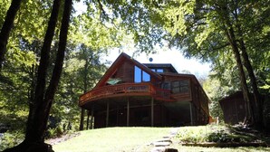 A wooden cabin with a balcony, surrounded by trees.