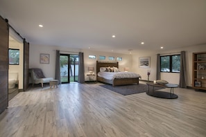 Une chambre spacieuse avec un grand lit, un coin salon avec une table et une vue sur l’extérieur grâce à une porte coulissante.