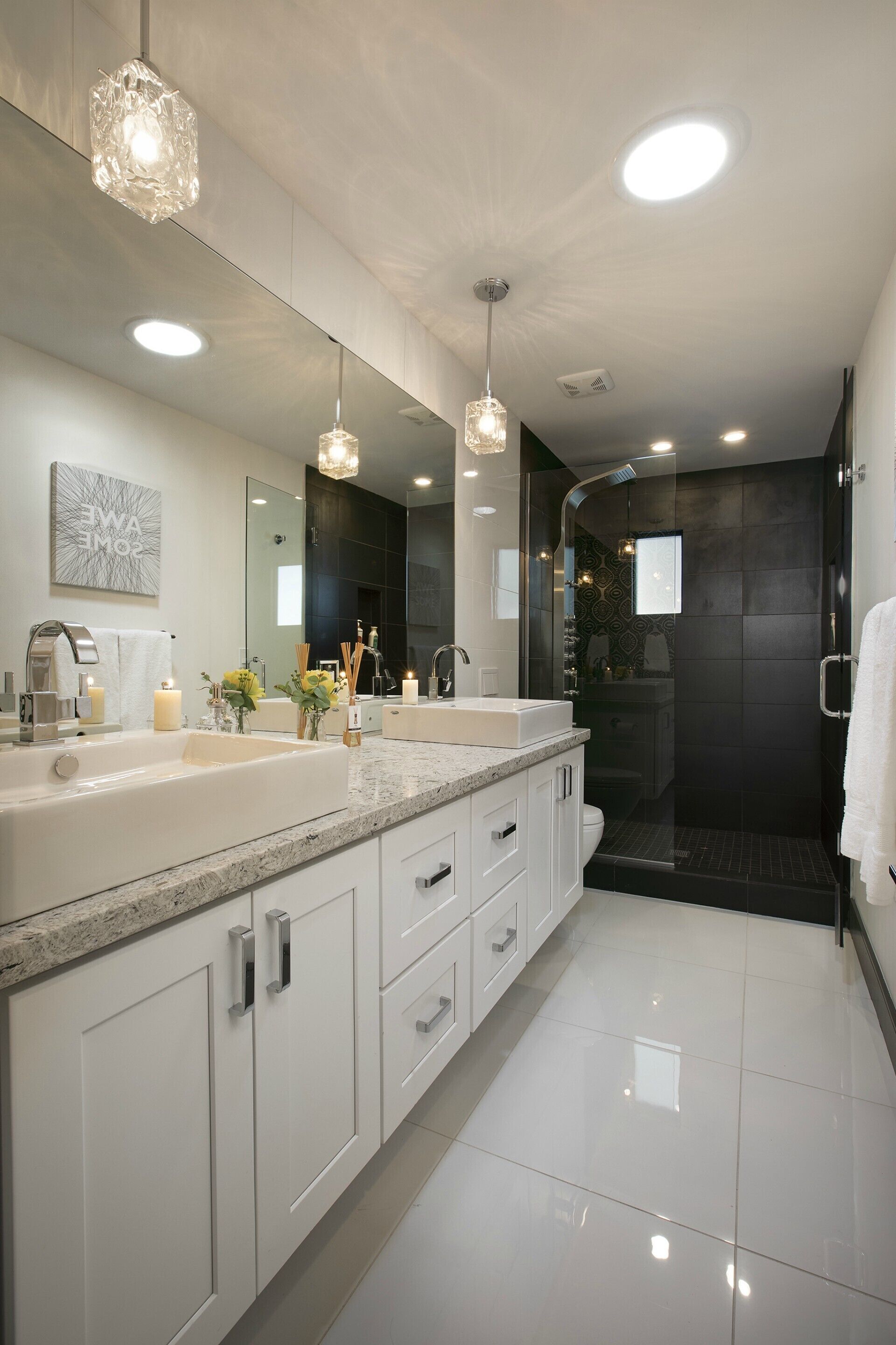 A modern bathroom with a large mirror, dual sinks, and a walk-in shower.