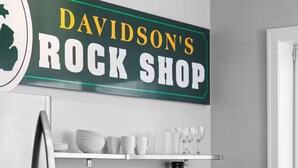 A kitchen with a sign reading 'DAVIDSON'S ROCK SHOP,' a refrigerator, microwave, and cabinets.