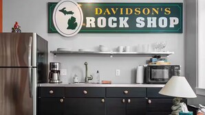 A kitchen with a refrigerator, a coffee maker, a microwave, and a sign above the counter that reads 'DAVIDSON'S ROCK SHOP'.