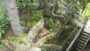 Een stenen keermuur met een kleine tuin, omringd door bomen en planten.