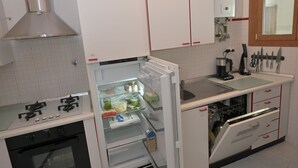 Een kleine keuken met een inbouwoven, een koelkast en een spoelbak.