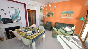 Een eetgedeelte met een gedekte tafel, een open haard en een bank in een woonkamer met oranje wanden.