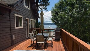 Eine Terrasse mit Whirlpool, Gartenmöbeln und Blick auf ein Gewässer.