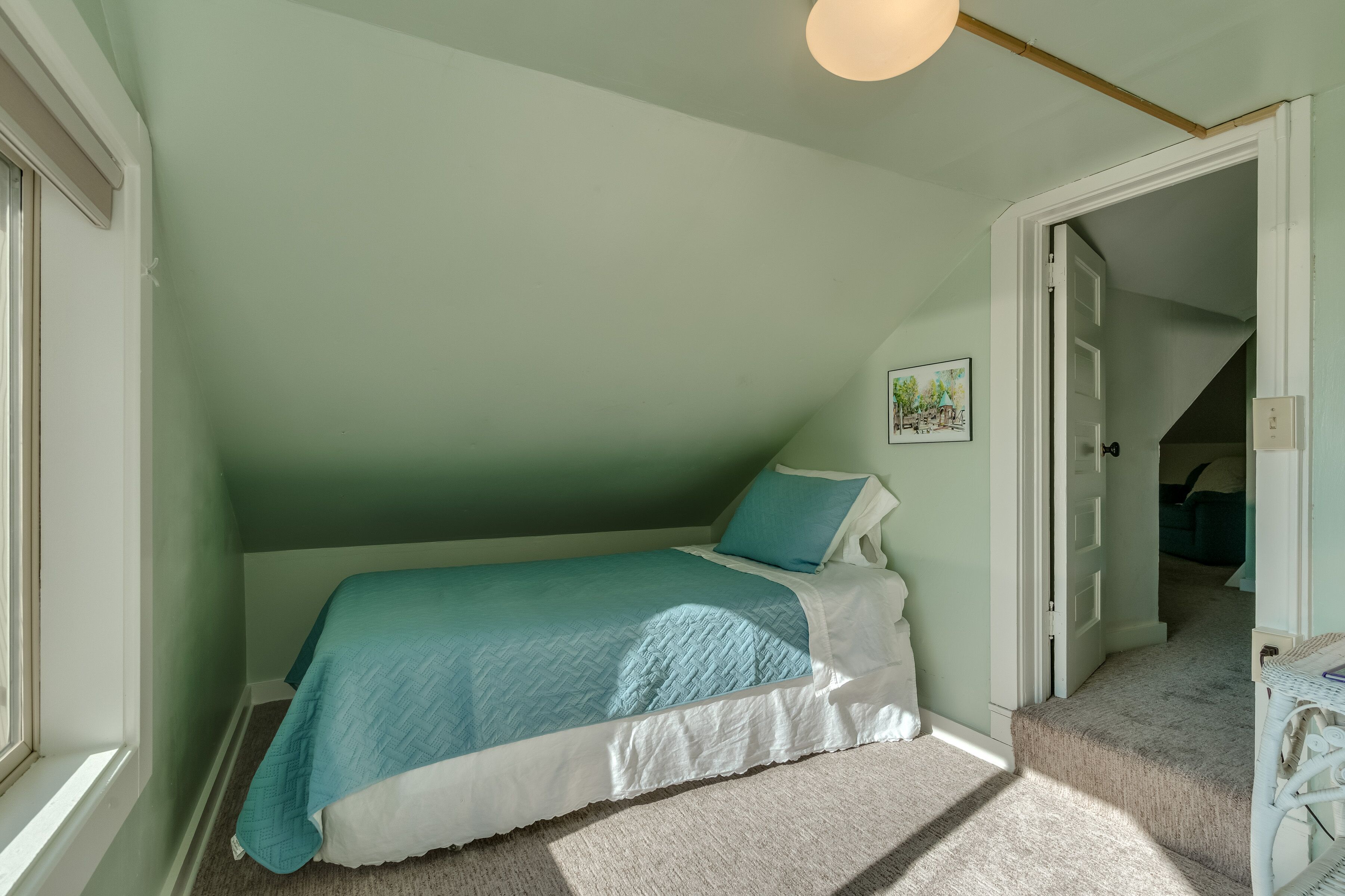 Ein Schlafzimmer mit Bett, Fenster und einer Tür zu einem anderen Raum.