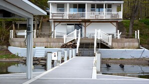 Una casa frente al agua con un muelle que conduce a una zona cubierta con escaleras.