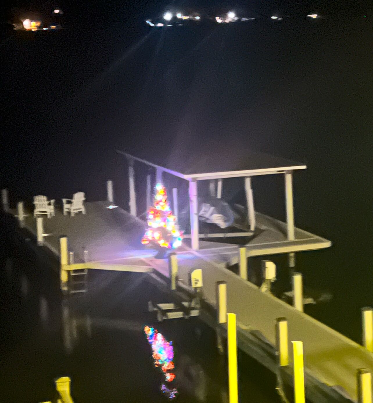 A dock with a Christmas tree and chairs.