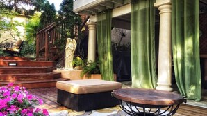 Un patio con una estatua, un banco acolchado y una mesa con base de cobre.
