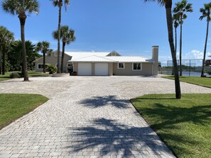 Une maison moderne à deux étages avec une allée pavée menant à un garage.