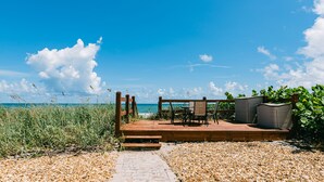 Una terraza de madera con una mesa y sillas, con vistas al océano.