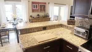 A modern kitchen with granite countertops, dark cabinetry, and stainless steel appliances. - ☀️ Outstandning & Lavish Luxury Villa ☀️ Private Pool & Spa & Golf Course View ⛳ (Haines City)
