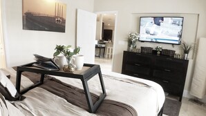 A bedroom with a bed, a bedside table with a tray, a TV, a dresser, and a painting on the wall. - ☀️ Outstandning & Lavish Luxury Villa ☀️ Private Pool & Spa & Golf Course View ⛳ (Haines City)