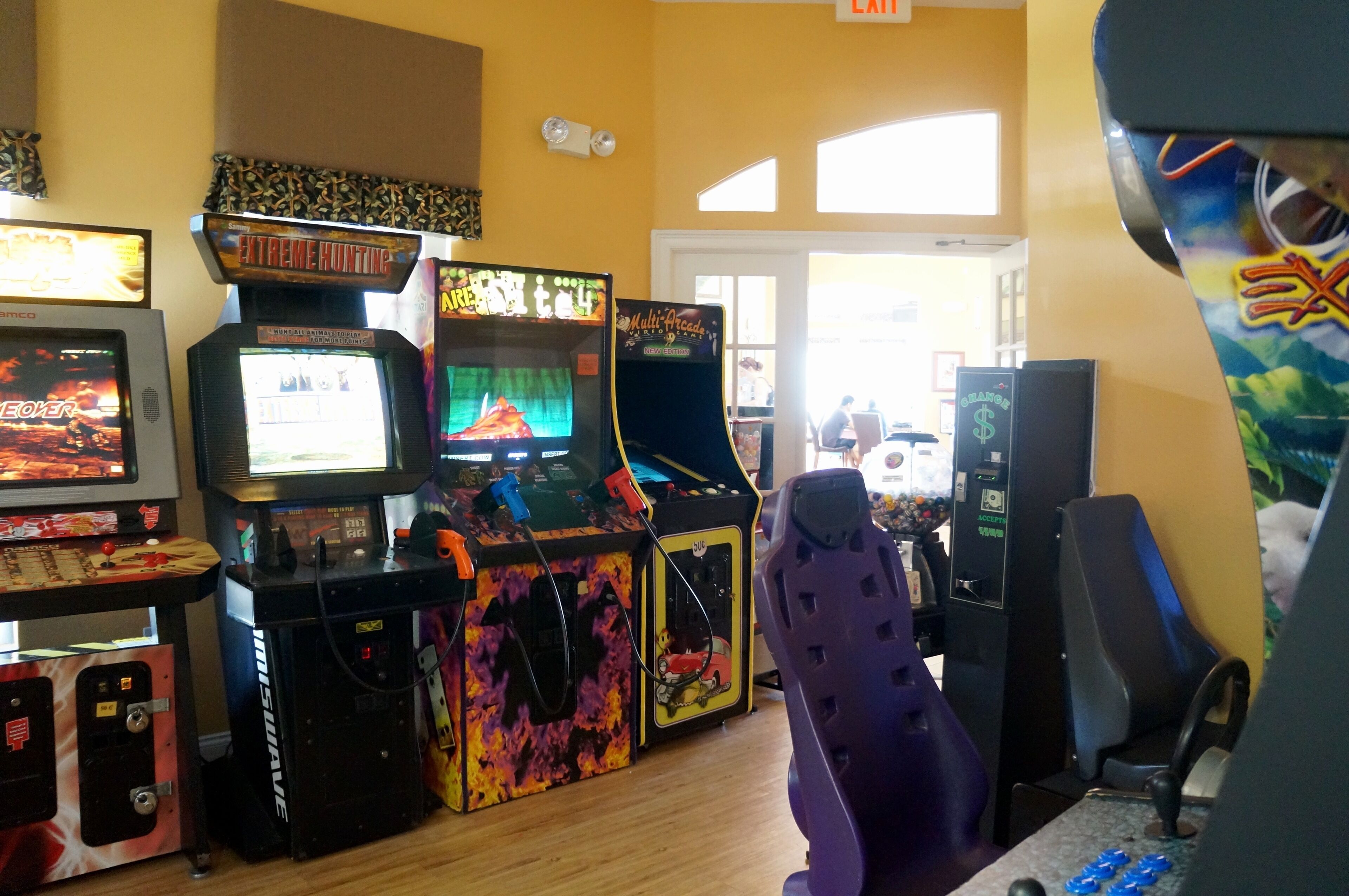 A gaming arcade with various arcade machines, including 'Extreme Hunting' and 'Multi-Across'.