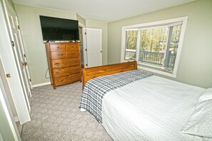 A bedroom with a bed, dresser, and TV.