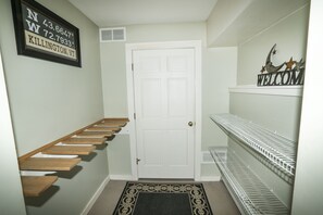 A hallway with a white door, wooden shelves, and metal shelves.
