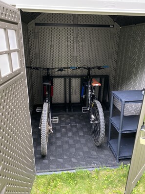 A garage with two bicycles, a red fire extinguisher, and a grey metal shelf.