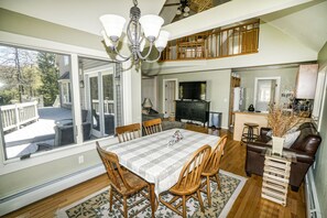 A spacious dining area with a large table and chairs, a kitchen with a TV, and a cozy living area with a fireplace.