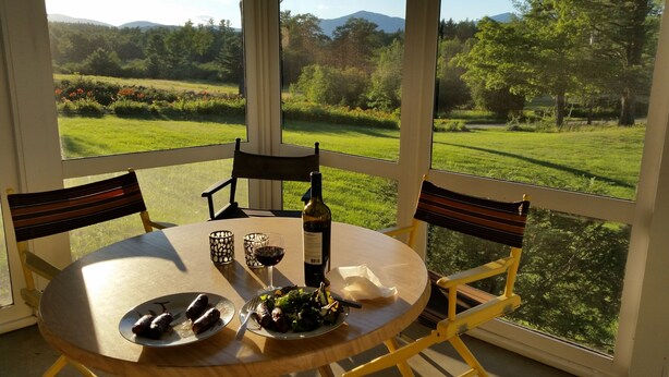 A dining table with chairs, a bottle of wine, and plates with food.