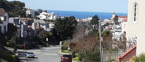 A residential street with houses, a church, and a view of the ocean.