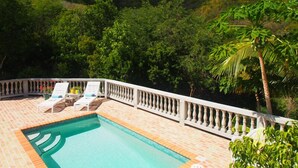A pool area with lounge chairs and a view of a mountainous landscape.