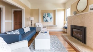 A living room with a blue sofa, white coffee table, and a fireplace.