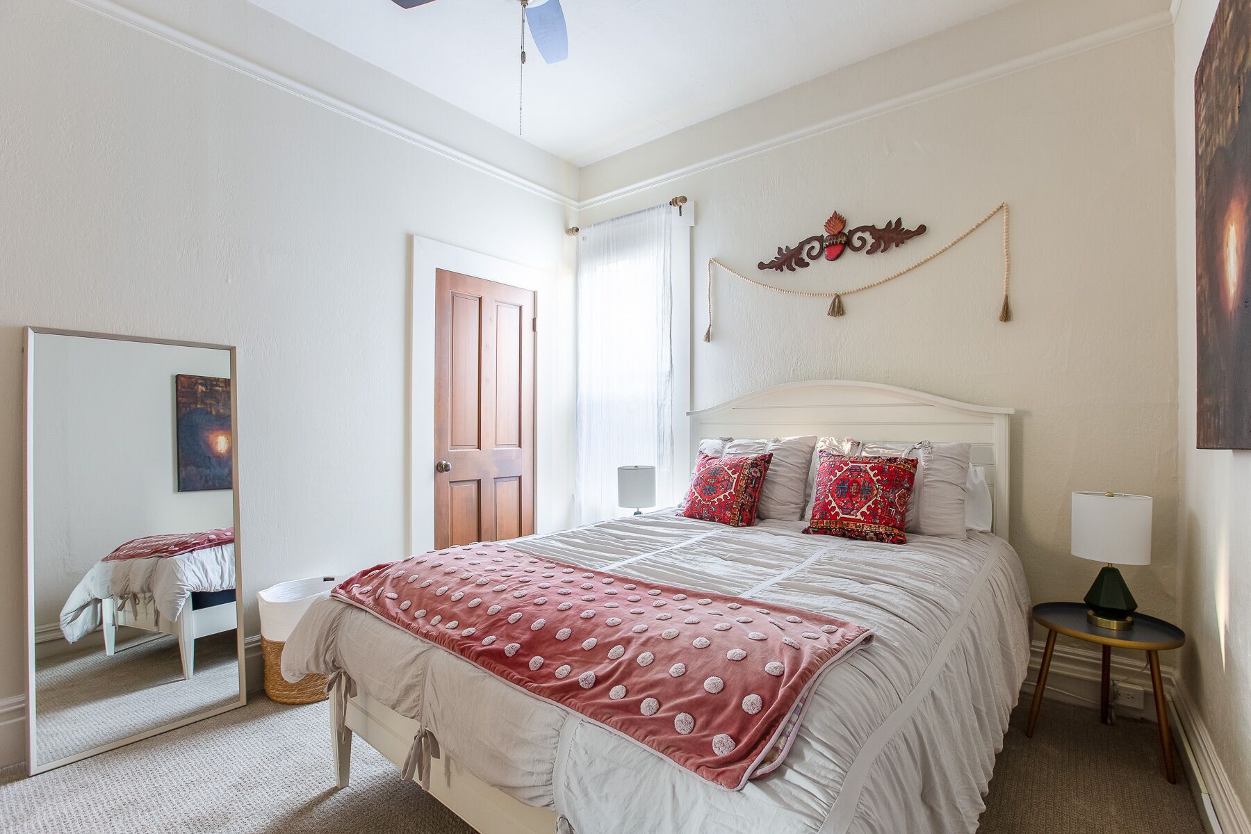 Une chambre à coucher avec un lit, un miroir, une porte et un élément décoratif fixé au mur.