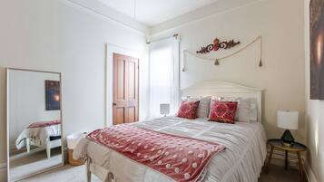 Une chambre à coucher avec un lit, un miroir, une porte et un élément décoratif fixé au mur.