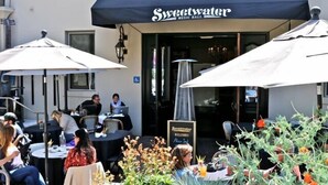 An outdoor seating area with tables and umbrellas at Sweetwater Music Hall.