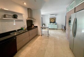 A modern kitchen with a dishwasher, stainless steel appliances, and a tiled floor.