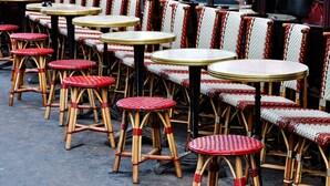 Outdoor seating with wicker chairs and round tables, arranged in rows.