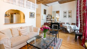 A living room with a sofa, coffee table, and a dining area with a table and chairs.