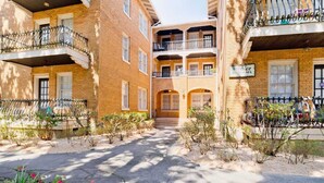A courtyard with brick buildings, balconies, and a sign indicating a restaurant. - Small Studio Condo -Private balcony -Free Parking (Mobile)