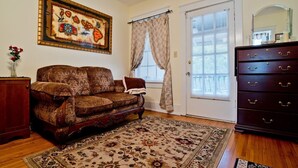 A living room with a patterned sofa, a wooden cabinet, a large rug, a dresser with drawers, and a framed picture on the wall. - Small Studio Condo -Private balcony -Free Parking (Mobile)