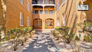 A courtyard with a brick building, a central entrance, and a sign indicating 'Windsor Apartments'. - Small Studio Condo -Private balcony -Free Parking (Mobile)