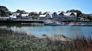 A waterfront property with multiple buildings, docked boats, and a pier extending into the water. - SEA PINES HARBOUR TOWN, NO STAIRS, 175 REVIEWS, IMMACULATE, PRIVATE, AND QUIET! (Sea Pines)
