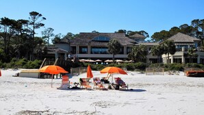 A beachfront property with a large building, beach umbrellas, and lounge chairs. - SEA PINES HARBOUR TOWN, NO STAIRS, 175 REVIEWS, IMMACULATE, PRIVATE, AND QUIET! (Sea Pines)