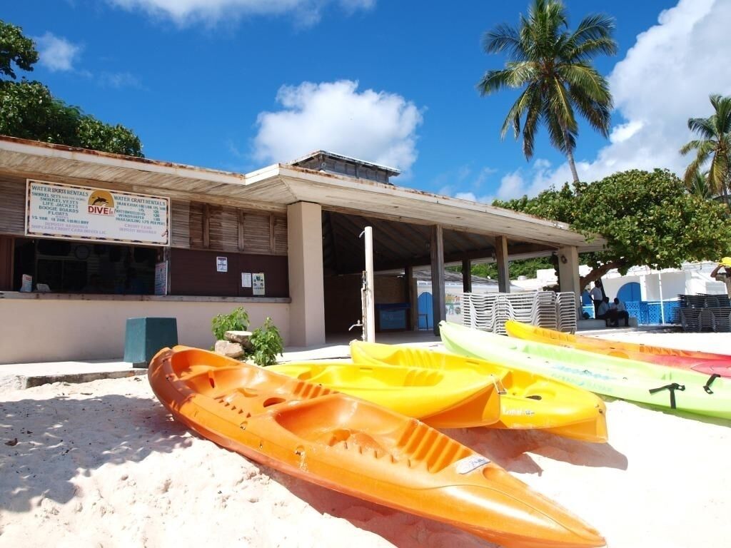 A building with a sign for water sports rentals and a covered area with kayaks.