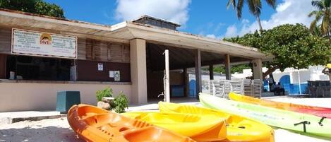 A building with a sign for water sports rentals and a covered area with kayaks.