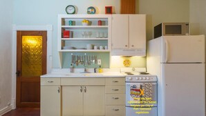 Cocina compacta con gabinetes blancos, estufa, microondas y refrigerador.