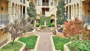 A courtyard with a central fountain, surrounded by greenery and a brick pathway. - Splendid, Tastful, And Fully Furnished Condo On Lake Travis Island Villa!!! (Lago Vista)