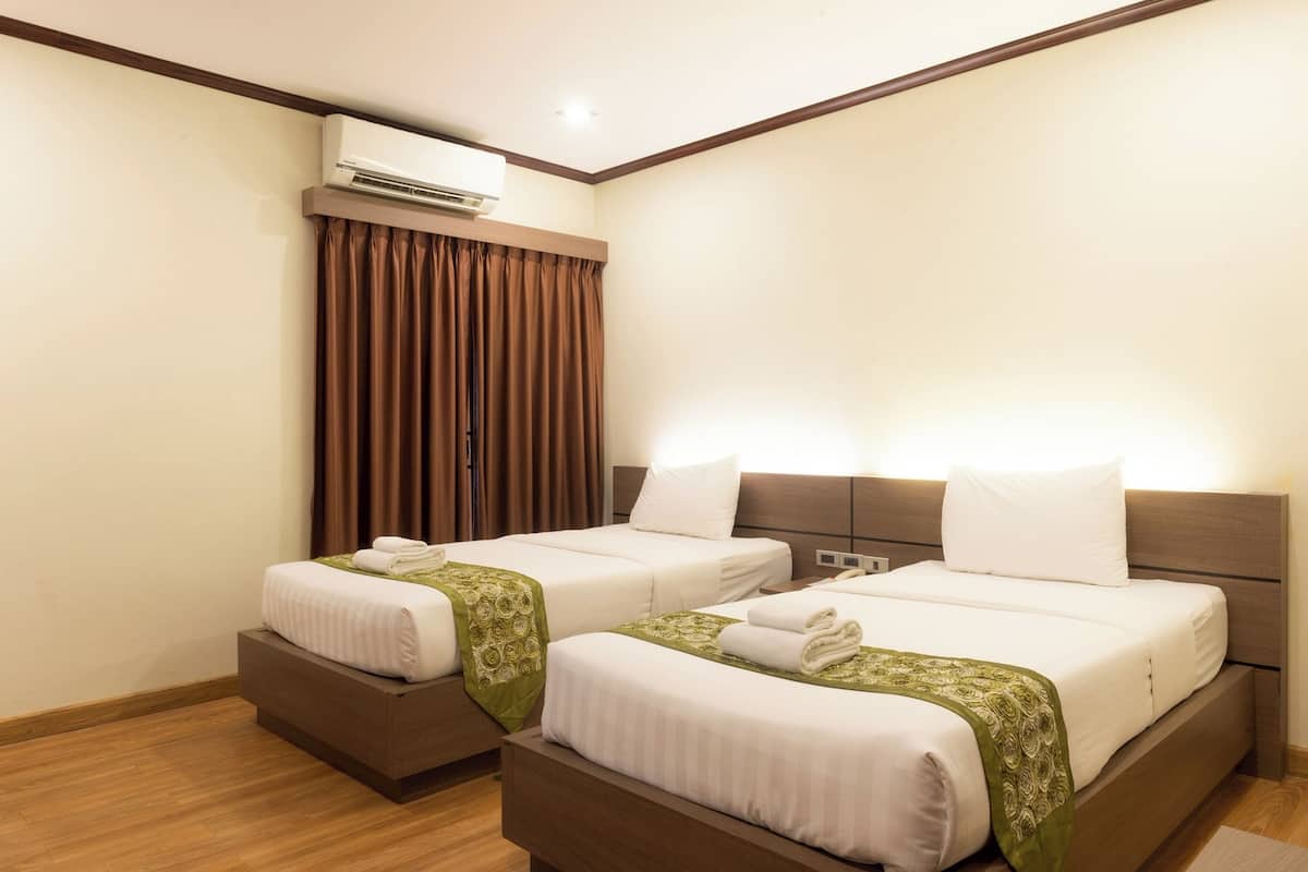 A hotel room with two beds, a large window with curtains, an air conditioning unit, and a wooden floor.