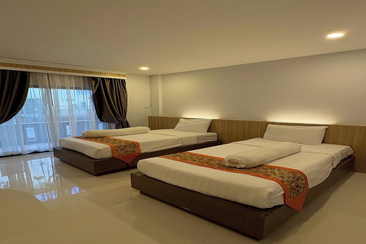 A hotel room with two beds, a large window with curtains, and a clean, modern design.