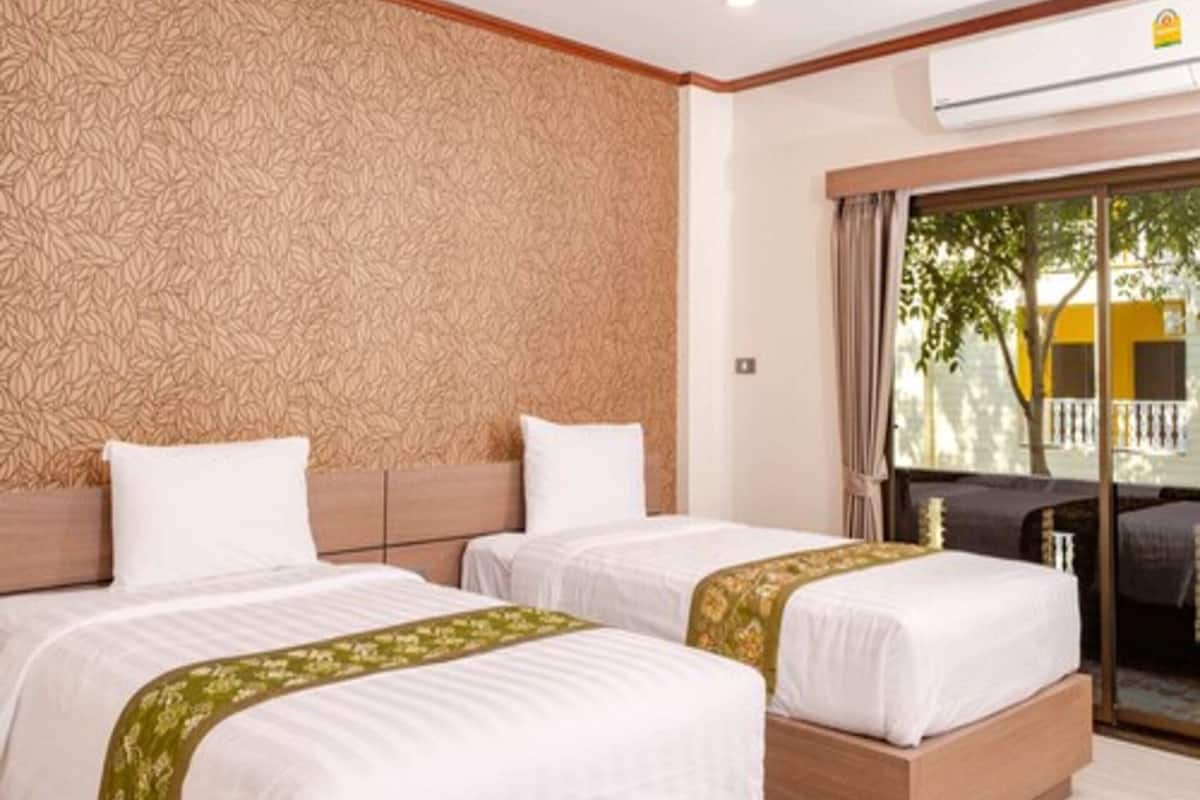 A hotel room with two beds, a patterned wall, and a view of the outside.