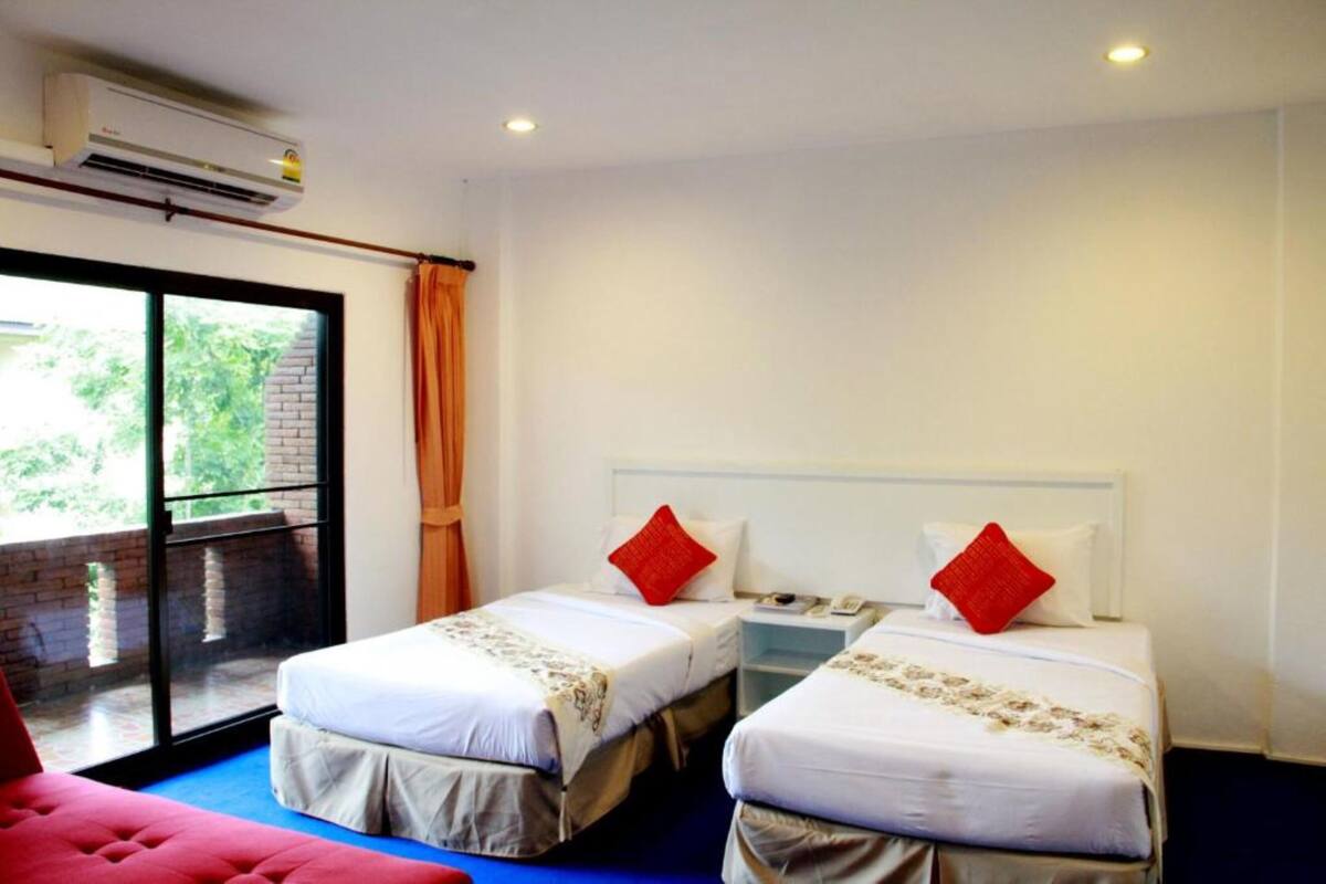 A hotel room with two beds, a large window, and an air conditioning unit.
