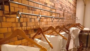 A bathroom with a brick wall, wooden hangers, and white towels. - NIM SEE SENG Hotel (Chiang Mai)