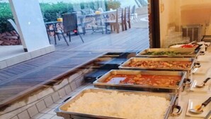 A buffet with various food options, including rice and different dishes, in a room with a view of a pier and ocean. - NIM SEE SENG Hotel (Chiang Mai)